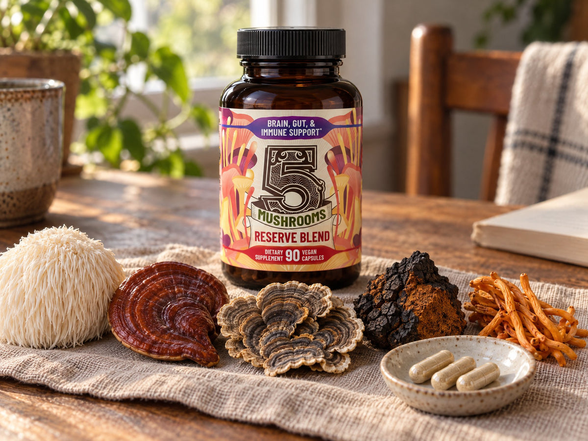 A bottle of 5 Mushrooms Reserve Blend behind lion's mane, reishi, turkey tail, chaga and cordyceps on a linen cloth