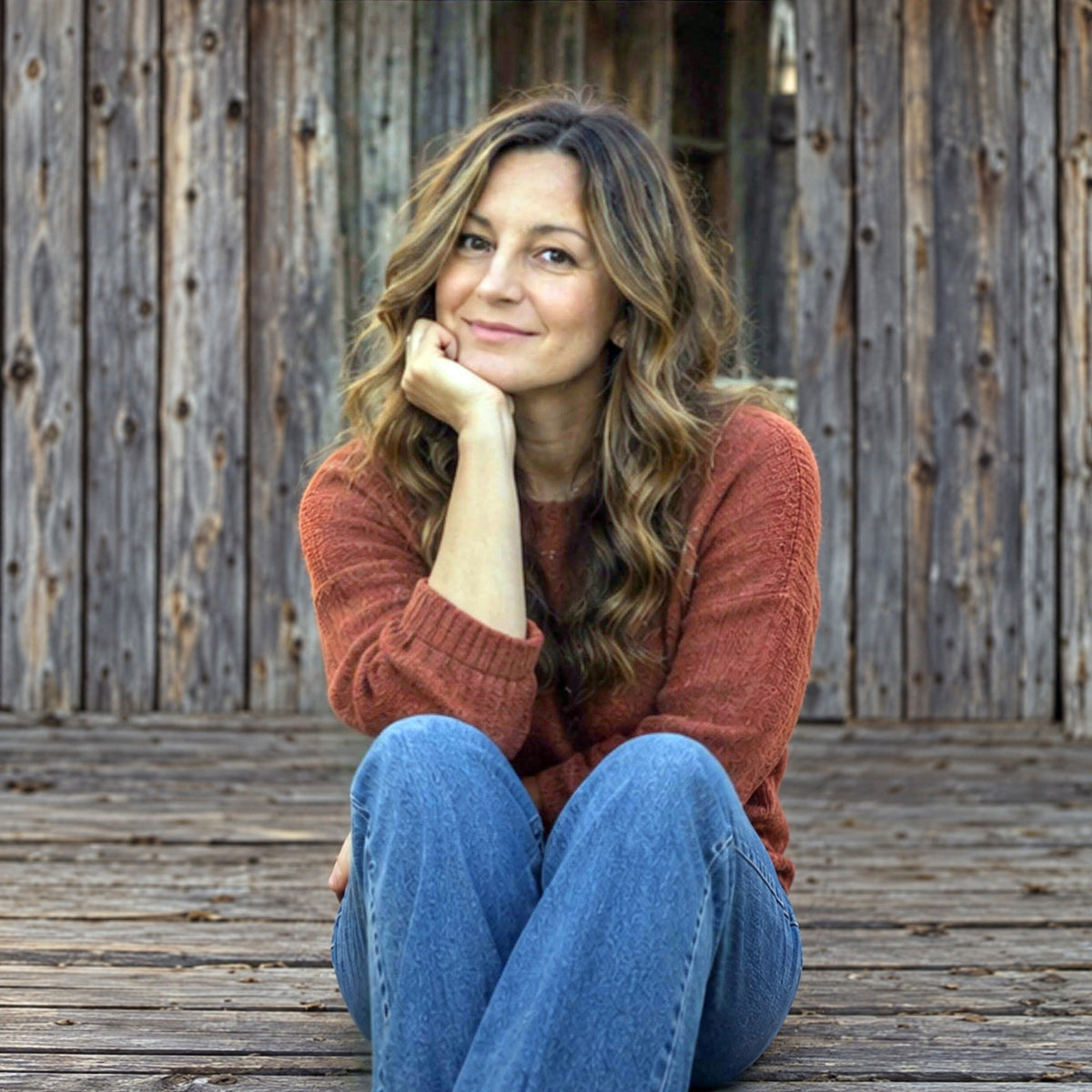 Ali Hogan, founder of Hippie Farms, sitting on a barn porch