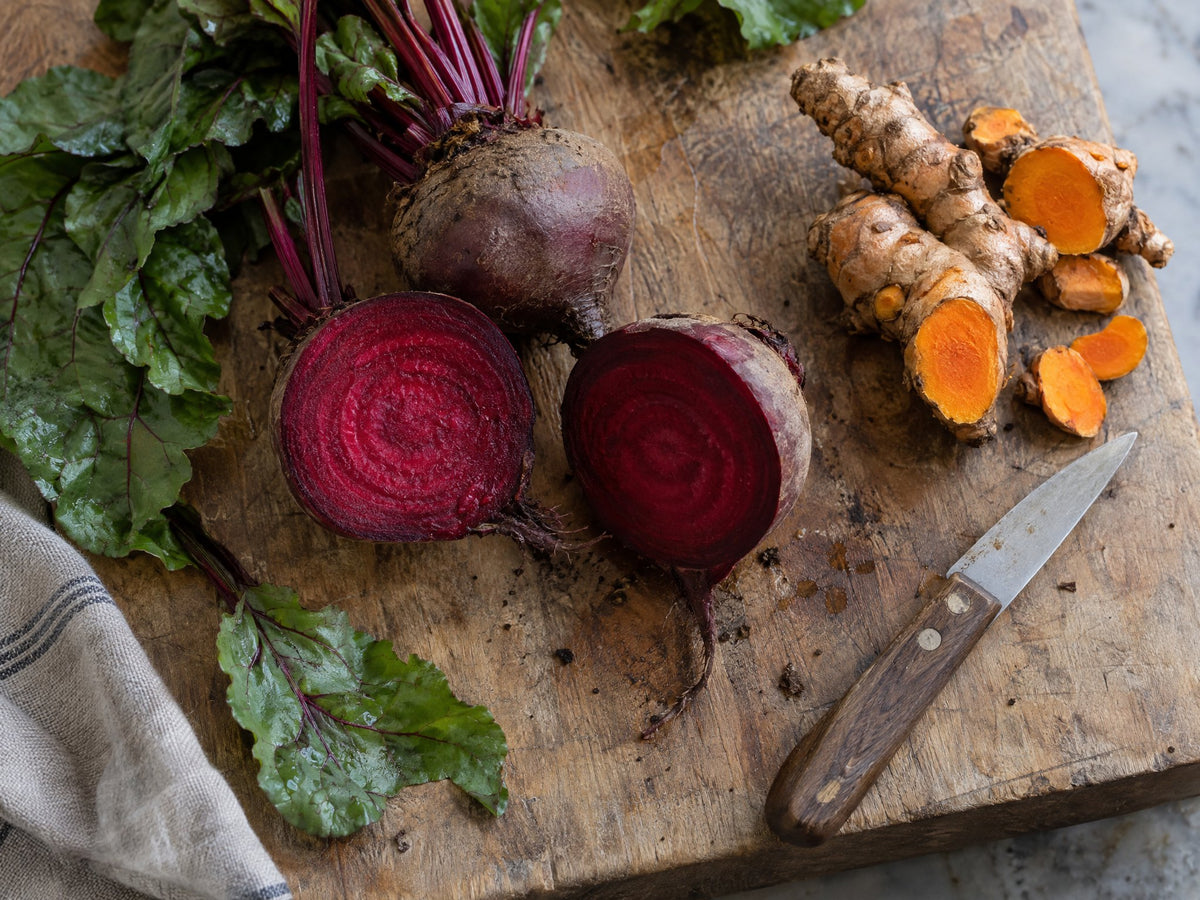 Halved beets and sliced turmeric root on a cutting board