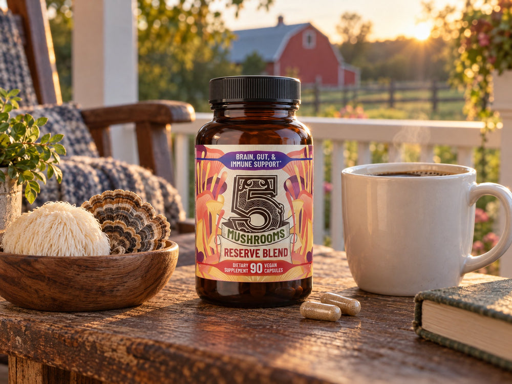 A bottle of 5 Mushrooms Reserve Blend next to a mug of coffee and fresh mushrooms on a farmhouse porch at golden hour